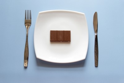 A bar of chocolate on a plate, with a knife and fork