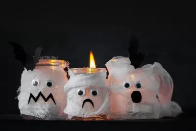 Adorable mummy luminaries made from candle jars - a charming homemade Halloween decoration!